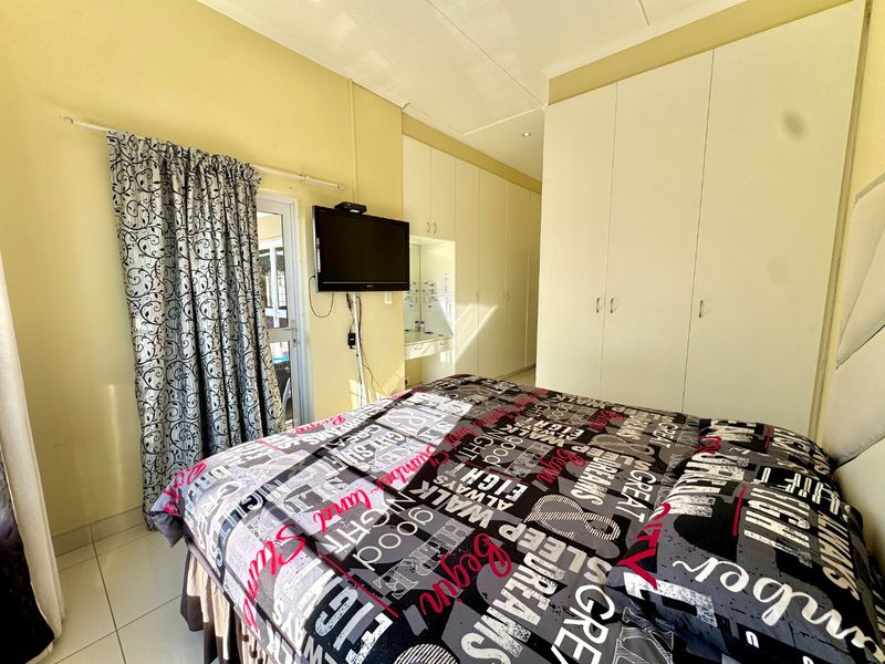 A bedroom featuring extensive built-in cupboards, tiled flooring, and a sliding door providing access to the exterior.