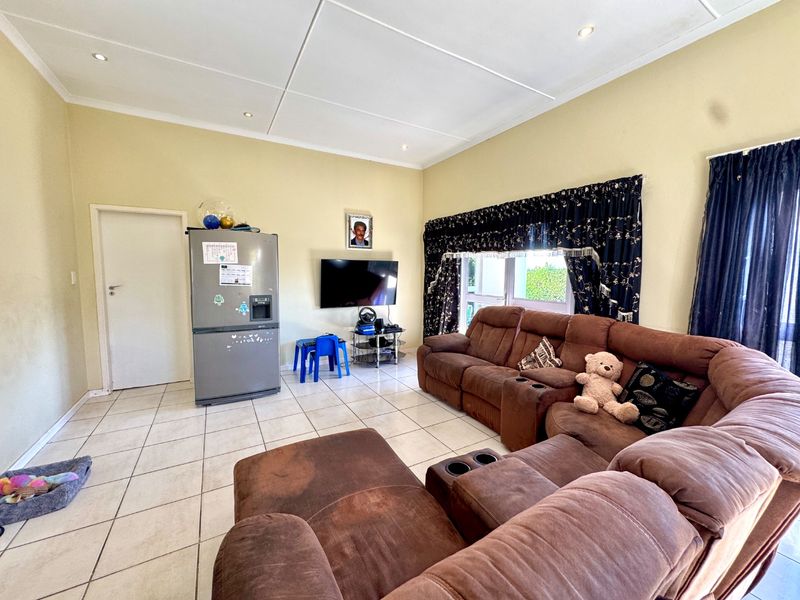 A spacious living room featuring tiled flooring, recessed downlighting, and a panelled ceiling, providing a functional and comfortable living area.