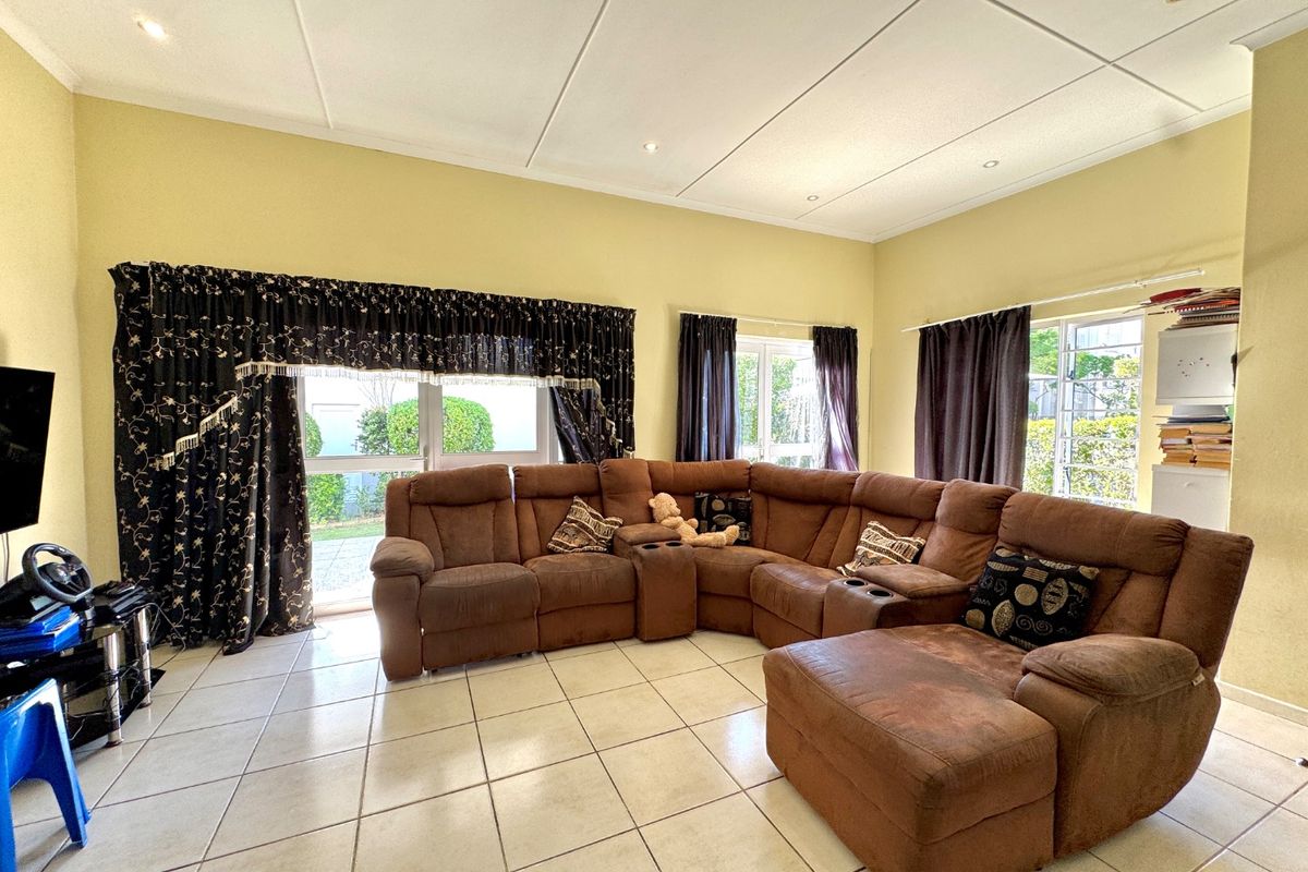 Spacious living room featuring tiled flooring, recessed downlighting, and large windows providing ample natural light and access to the outdoor area.