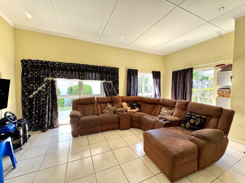 Spacious living room featuring tiled flooring, recessed downlighting, and large windows providing ample natural light and access to the outdoor area.