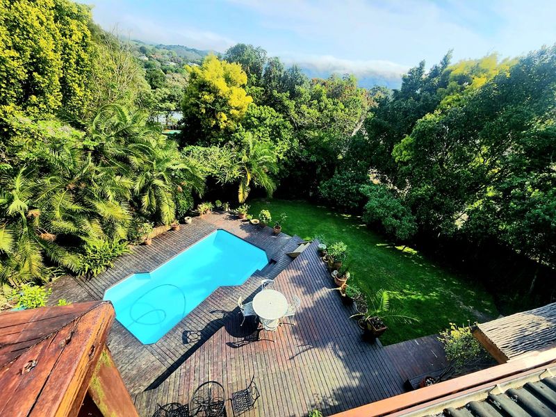 Elevated view of a private swimming pool set within a timber deck and lush, landscaped garden surroundings.