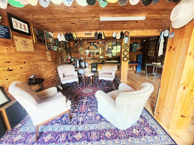 A rustic-style bar area featuring timber wall and ceiling cladding, a built-in bar counter, and timber flooring, creating a cozy entertainment space.