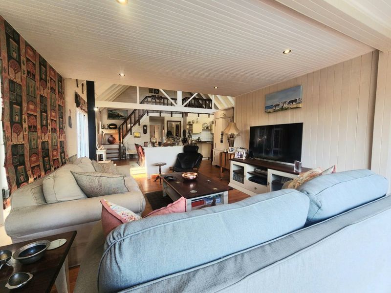 Spacious open-plan living area featuring timber flooring, tongue and groove ceilings, and a mezzanine level with staircase access.