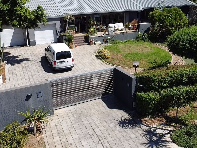Aerial view of a residential property featuring a paved driveway, sliding gate, double garage, and a raised patio area.