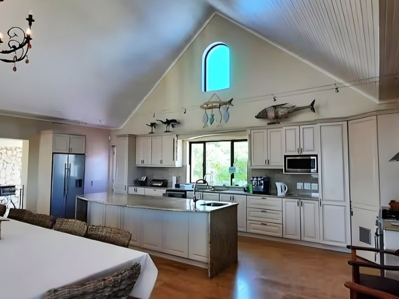 Spacious open-plan kitchen featuring a large island, vaulted ceilings, custom cabinetry, and an arched window, creating a bright and airy living space.