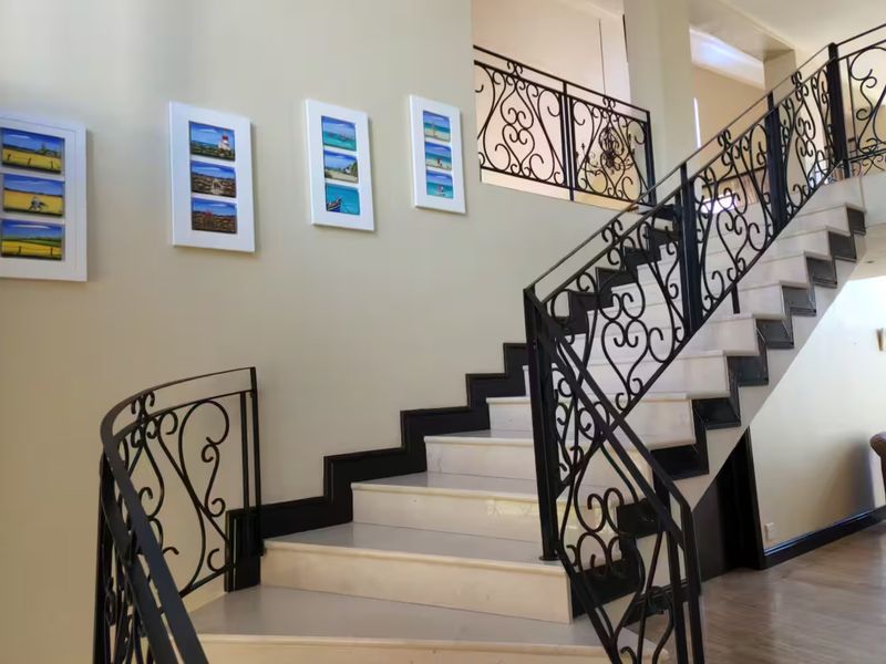 Elegant entrance foyer featuring a grand stone staircase with decorative wrought iron balustrades leading to an upper landing.