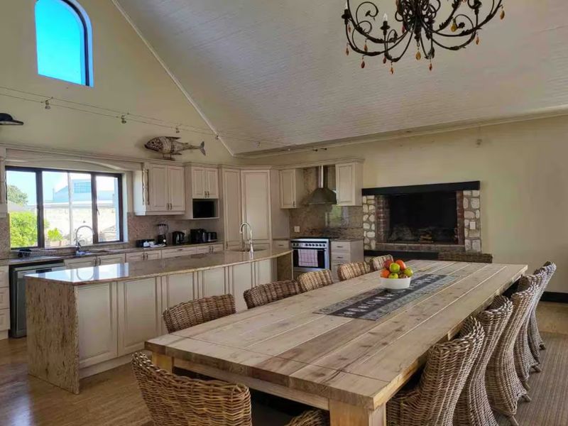 Spacious open-plan kitchen and dining area featuring a large island, granite countertops, built-in fireplace, and impressive vaulted ceilings with a feature chandelier.