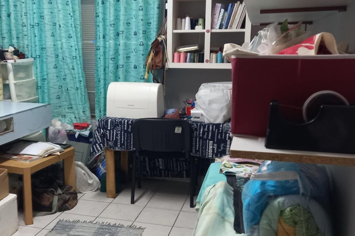 A multi-purpose room featuring tiled flooring and built-in wall shelving, currently utilized as a craft and workspace area.