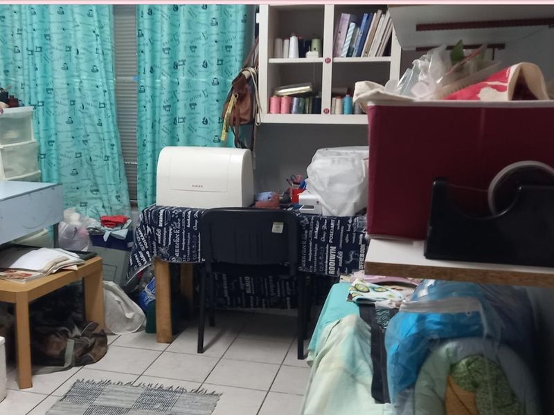 A multi-purpose room featuring tiled flooring and built-in wall shelving, currently utilized as a craft and workspace area.