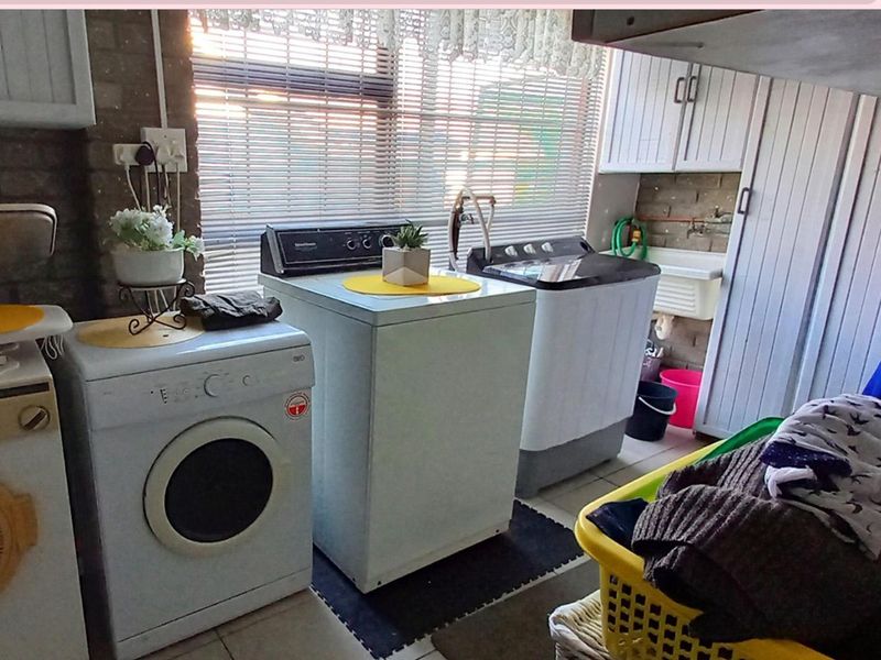 A functional laundry room featuring built-in cabinetry, a utility sink, and tiled flooring, providing practical space for washing and household utility tasks.