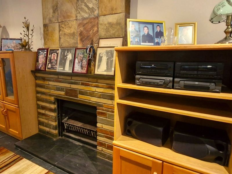 A living room featuring a prominent stone fireplace with a slate hearth and decorative stone tile chimney breast.