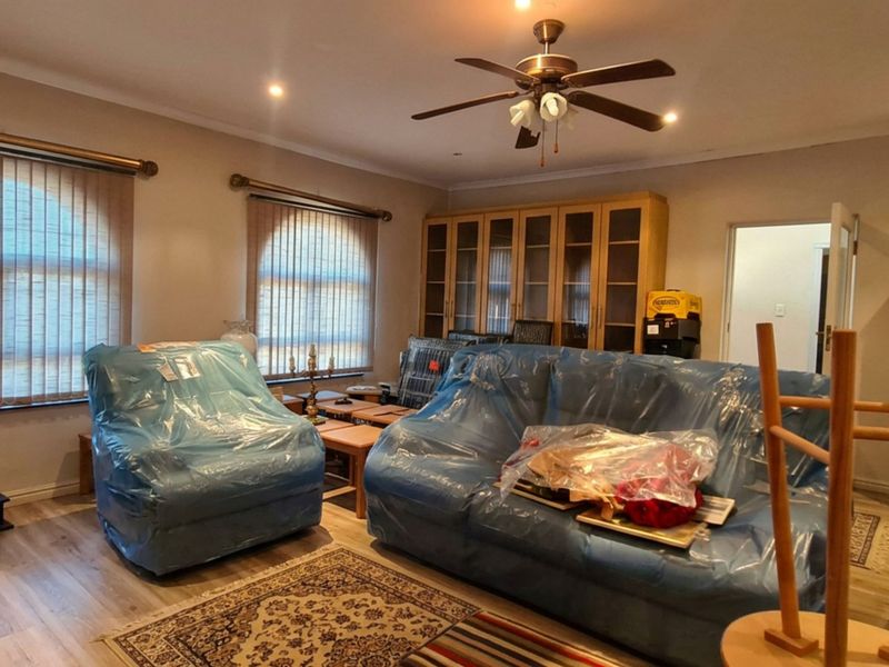 Spacious living room featuring laminate flooring, recessed lighting, a ceiling fan, and built-in storage cabinetry.