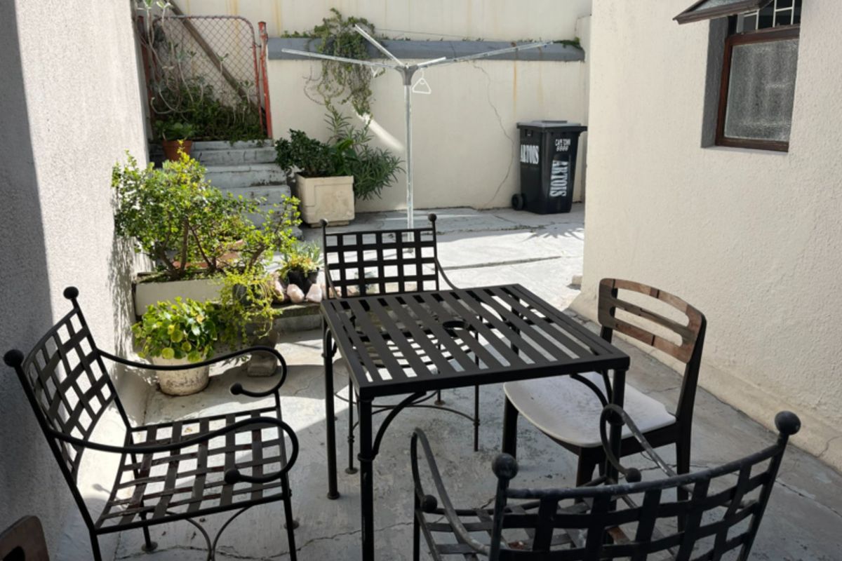 A paved rear courtyard area featuring a retaining wall, security gate, and rotary clothesline, offering potential for outdoor improvement and landscaping.