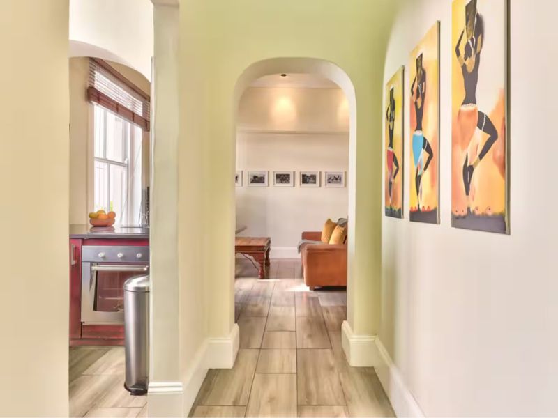 A bright hallway featuring arched architectural detailing, tiled flooring, and recessed lighting, providing a seamless transition between the living area and kitchen.