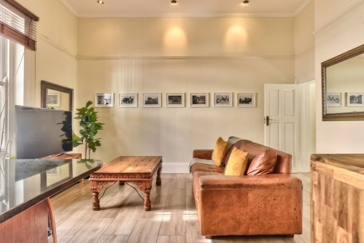 A well-lit living room featuring timber-look flooring, recessed downlighting, and neutral wall finishes, creating a comfortable and inviting atmosphere.