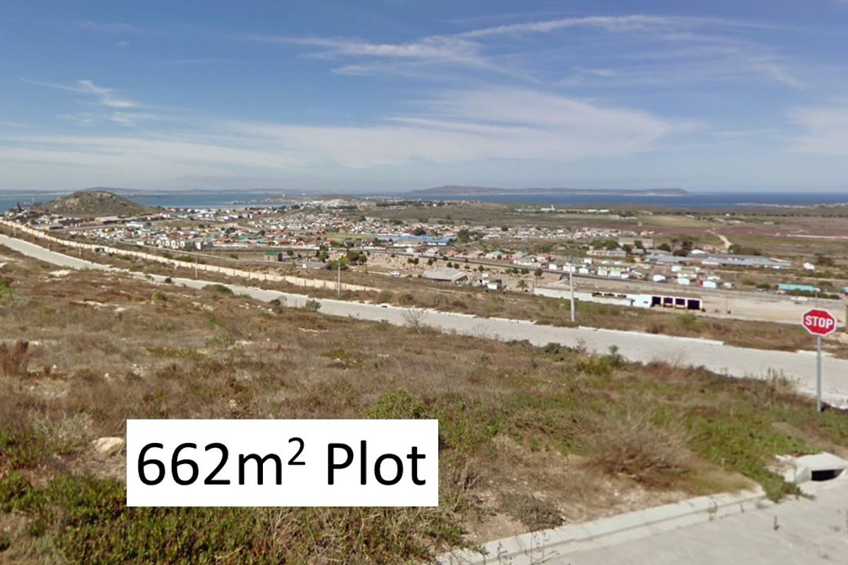 Elevated view overlooking a coastal residential area and surrounding landscape, featuring a vacant plot of land in the foreground.
