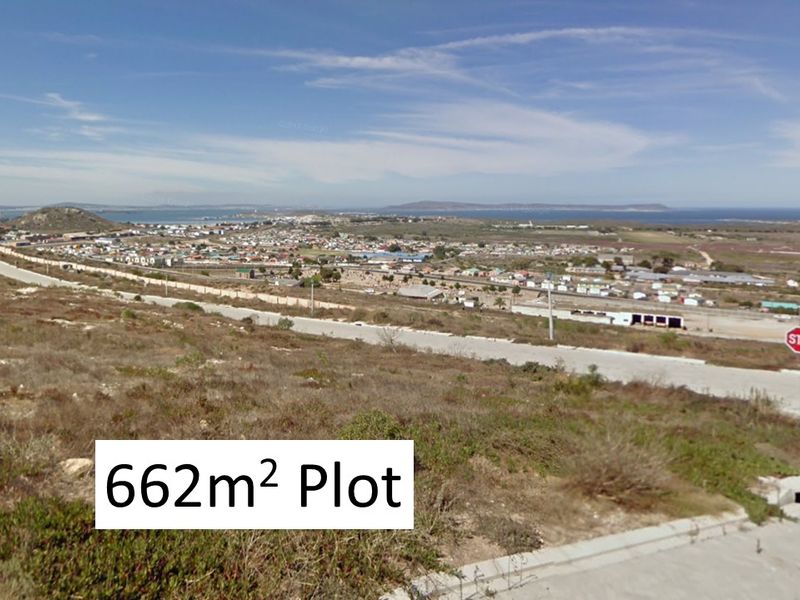 Elevated view overlooking a coastal residential area and surrounding landscape, featuring a vacant plot of land in the foreground.