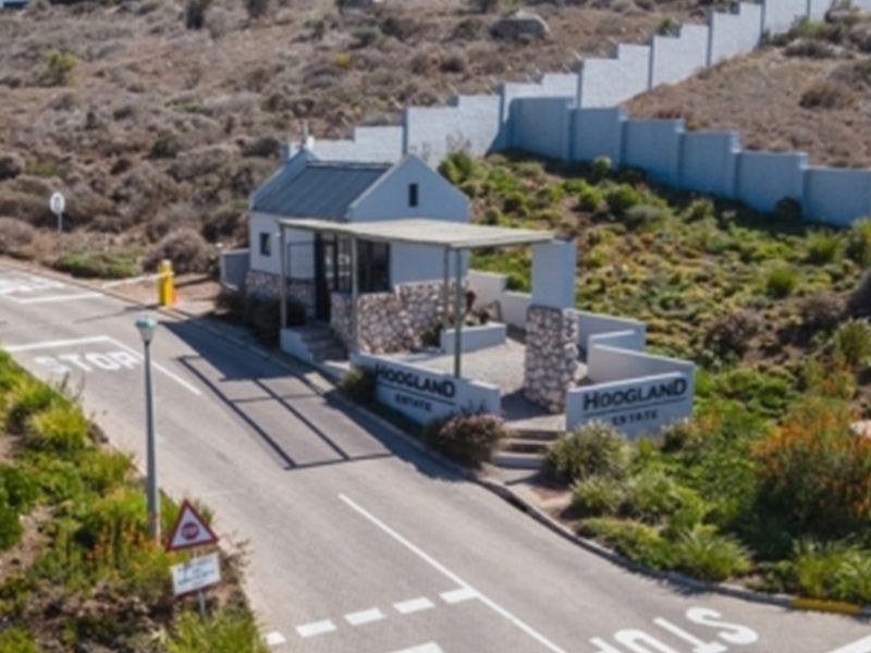Aerial view of the Hoogland Estate security entrance featuring a stone-clad gatehouse, boom gate access, and paved driveway.