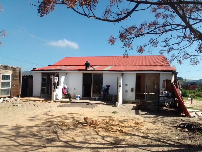Rear view of a single-story house currently undergoing roof repairs and exterior maintenance.