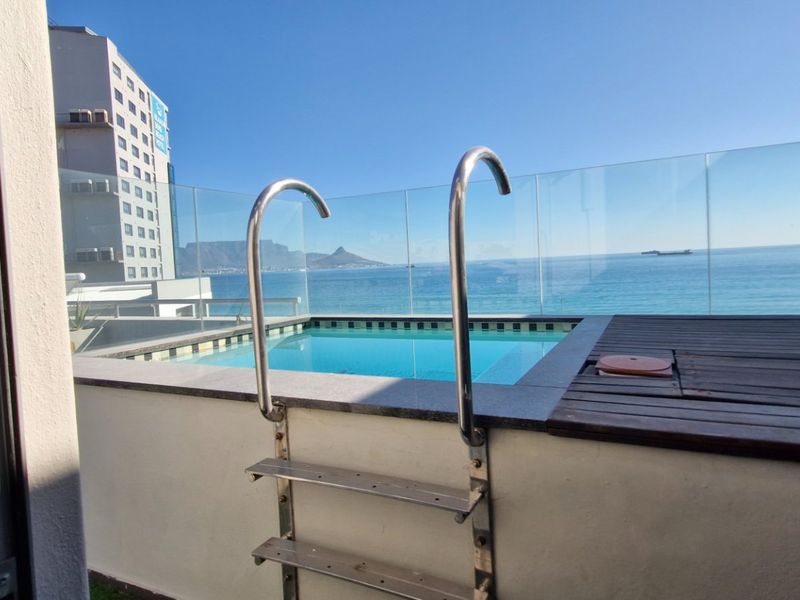 A private plunge pool featuring a glass balustrade and timber decking, offering stunning ocean and mountain views.