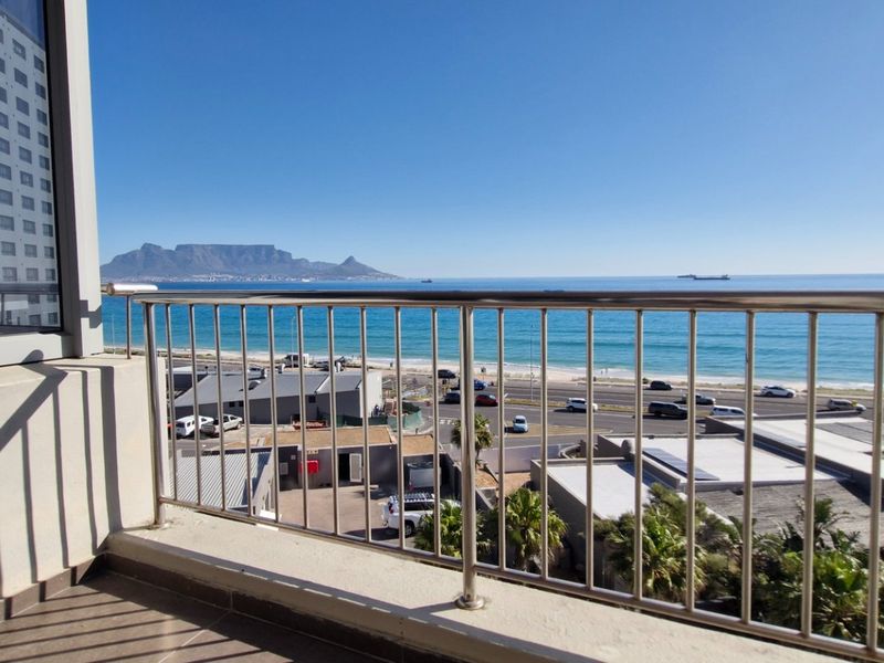 A balcony featuring a stainless steel balustrade and tiled flooring, offering expansive views of the ocean and Table Mountain.