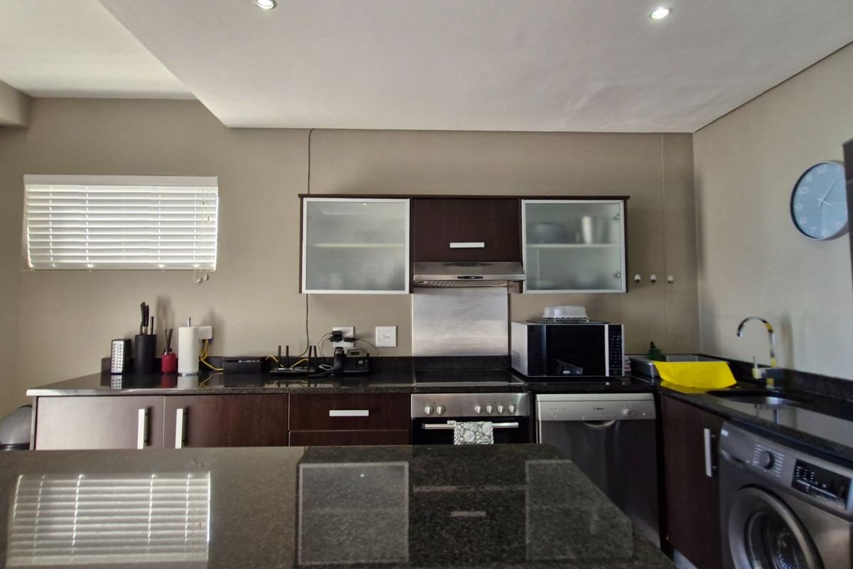 Modern kitchen featuring dark wood cabinetry, granite countertops, stainless steel appliances, and recessed downlighting, offering a functional and contemporary cooking space.
