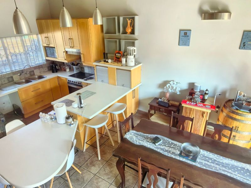 Open-plan kitchen and dining area featuring wooden cabinetry, laminate countertops, built-in appliances, and tiled flooring, offering a functional layout for daily living.