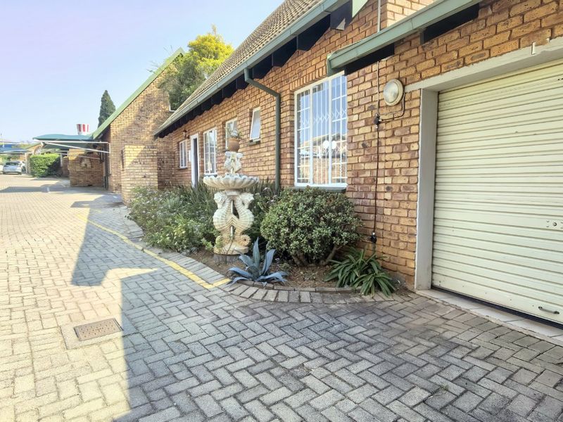 Front exterior view of the townhouse featuring a brick facade, paved driveway, and a secure roller garage door.