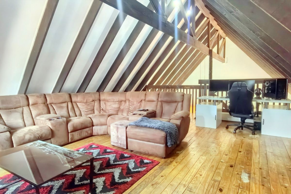 Spacious attic-style living area featuring exposed timber rafters, vaulted ceilings, and polished timber flooring, offering a unique and character-filled living space.