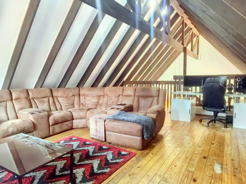 Spacious attic-style living area featuring exposed timber rafters, vaulted ceilings, and polished timber flooring, offering a unique and character-filled living space.