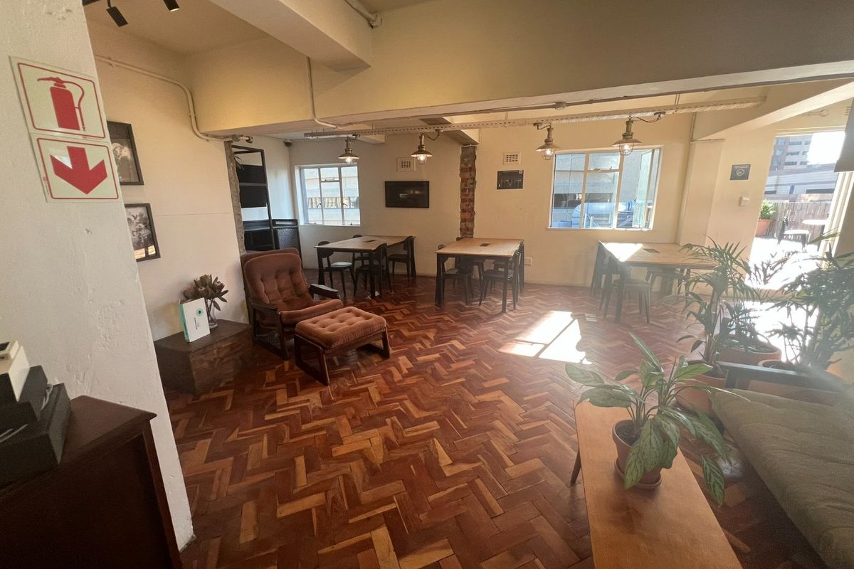 Spacious open-plan area featuring classic herringbone parquet flooring, industrial-style exposed ceiling beams, and large steel-framed windows providing ample natural light.