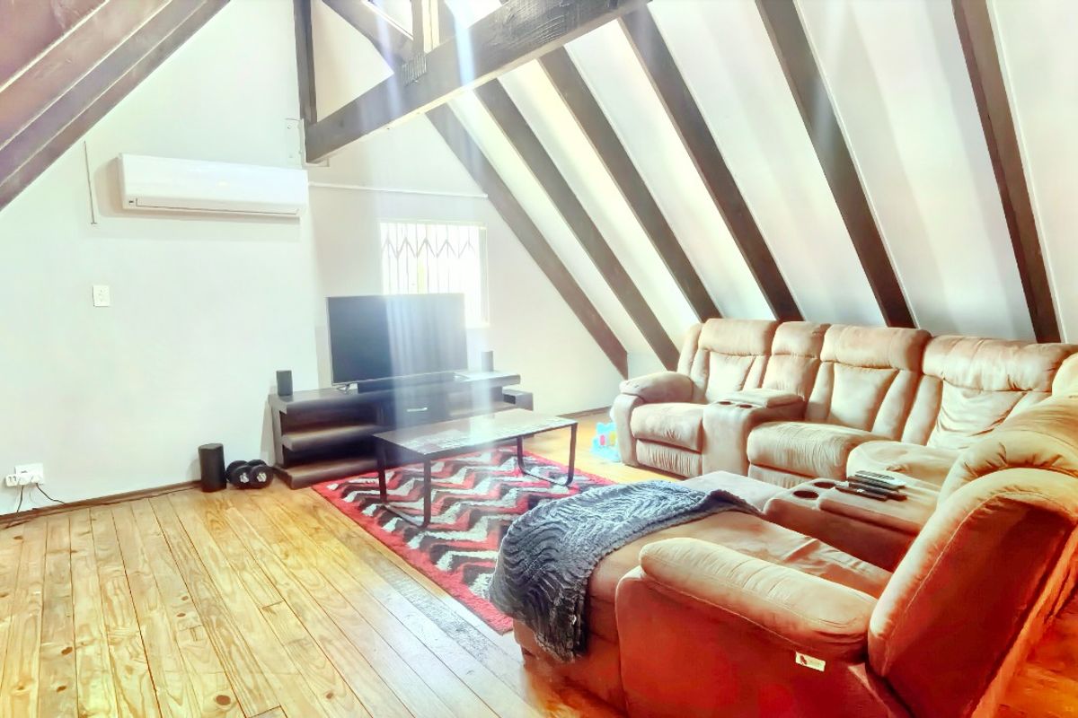 Spacious living room featuring a vaulted ceiling with exposed timber rafters, timber flooring, and a wall-mounted split-system air conditioner.