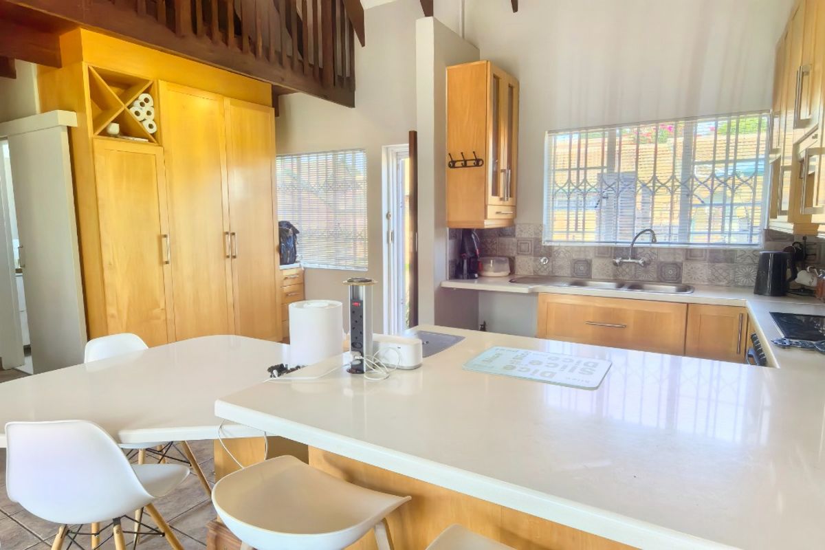 Open plan kitchen featuring wooden cabinetry, a central island, and a mezzanine level, with tiled flooring and natural light from windowed areas.