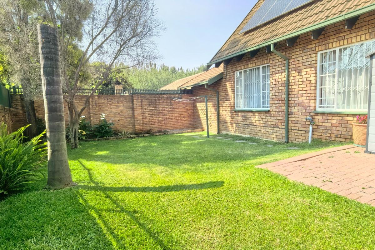 A private rear garden featuring a brick-paved patio area, established lawn, and secure perimeter walling, with solar panels installed on the roof.