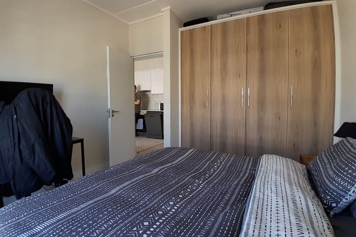 A bedroom featuring a large, modern wood-finish built-in wardrobe with ample storage space.