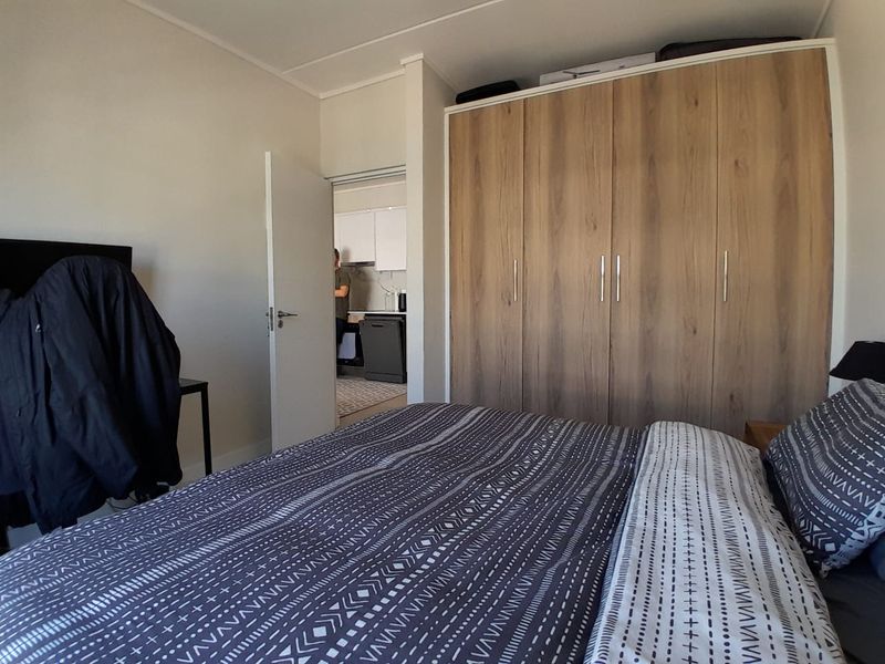 A bedroom featuring a large, modern wood-finish built-in wardrobe with ample storage space.