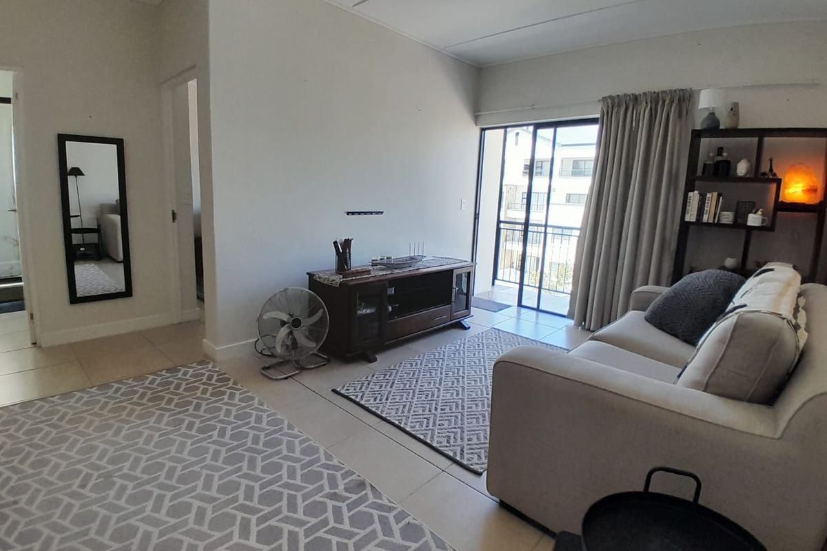 A living room featuring tiled flooring and a sliding glass door that provides access to an outdoor balcony area.