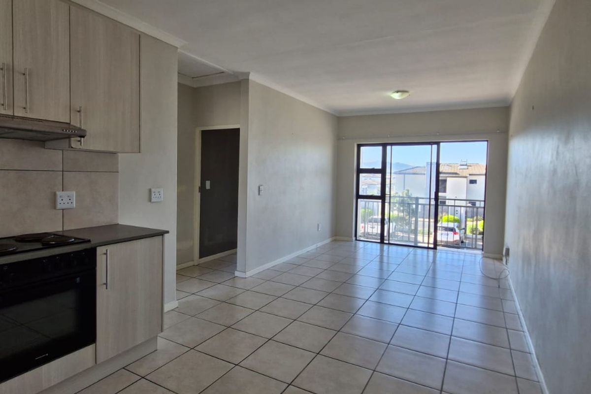Open-plan kitchen and living area featuring tiled flooring, built-in cabinetry, and a sliding glass door leading to a balcony.