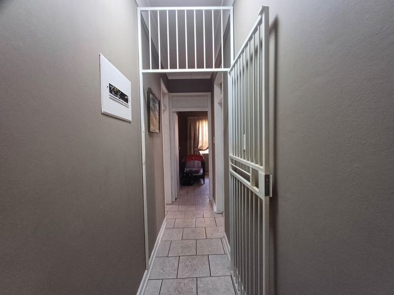 A functional hallway featuring tiled flooring and a white security gate, providing access to the interior living spaces.