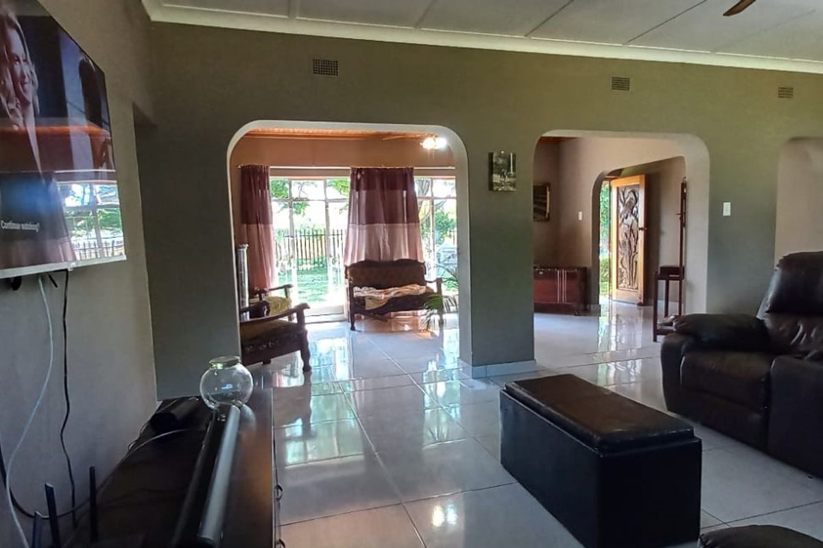 Spacious living area featuring tiled flooring, arched architectural transitions, and direct access to the outdoor patio through sliding glass doors.