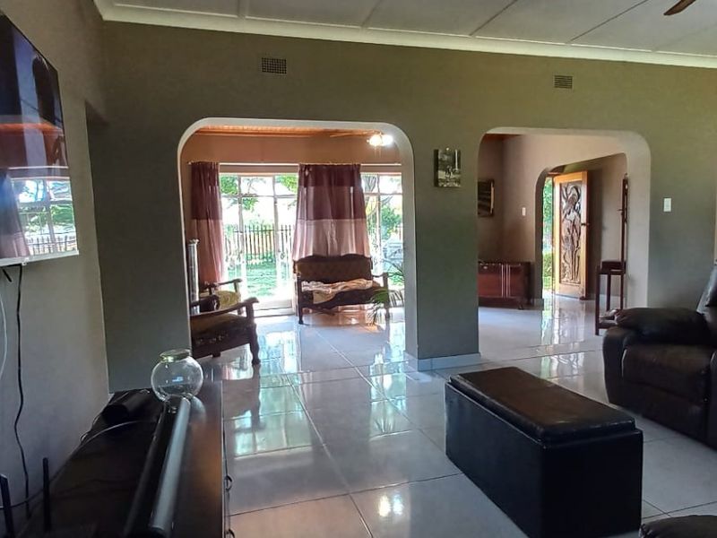 Spacious living area featuring tiled flooring, arched architectural transitions, and direct access to the outdoor patio through sliding glass doors.