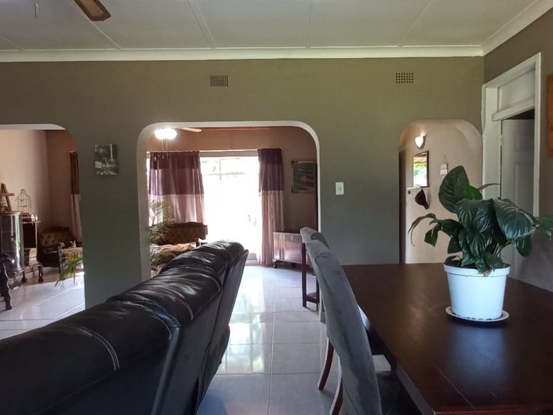 Spacious open-plan living and dining area featuring tiled flooring, arched architectural transitions, and a neutral color palette.