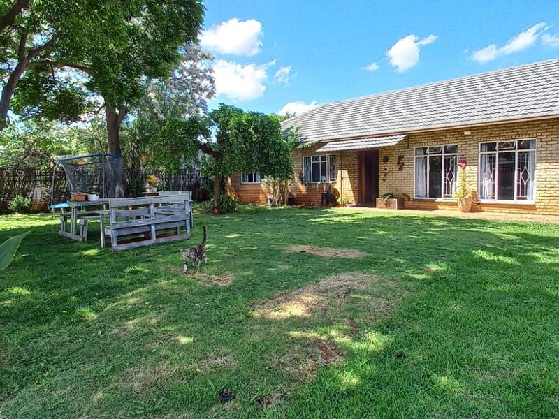 A view of the rear exterior of the house featuring a brick facade, tiled roof, and a spacious garden area.
