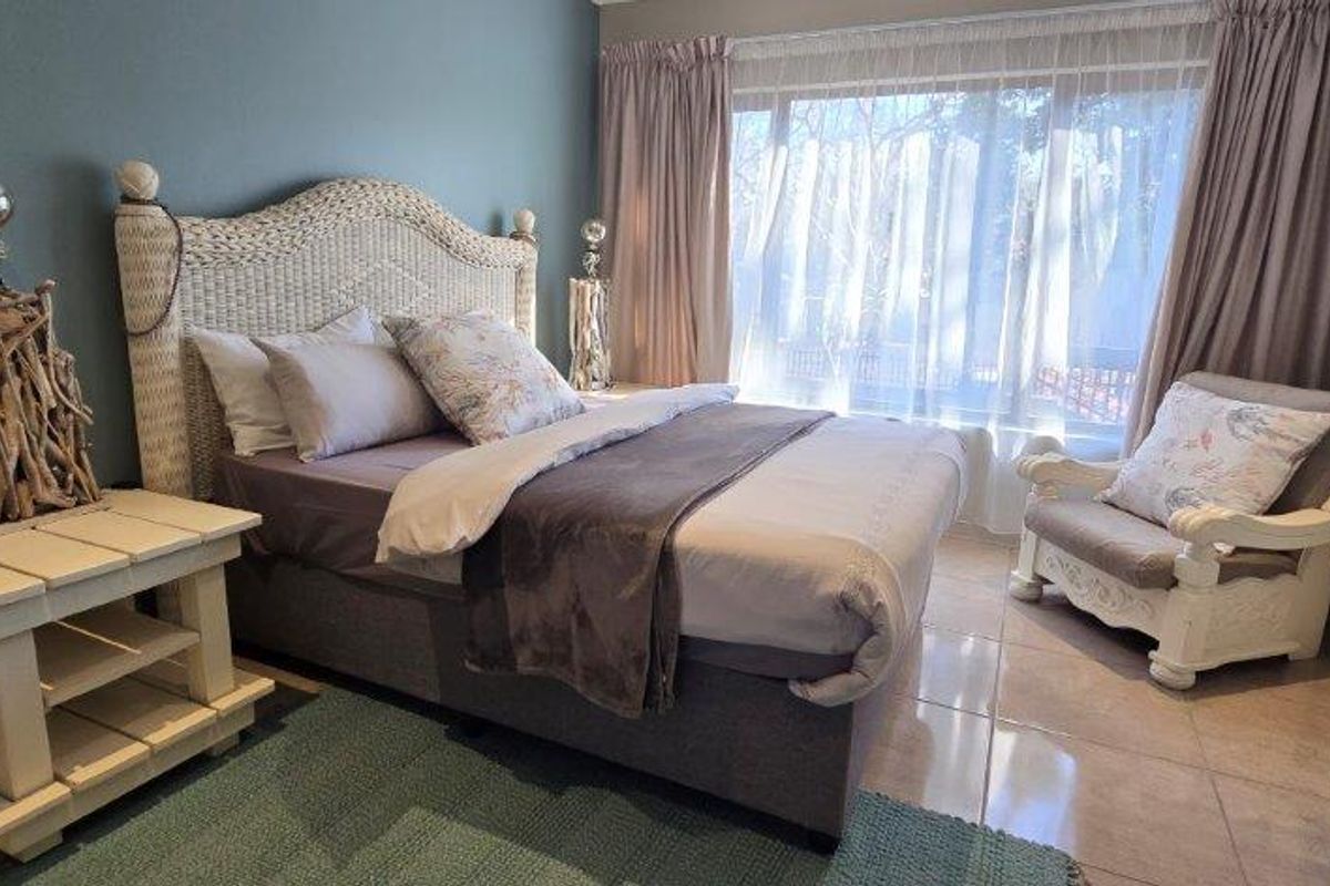 A comfortable bedroom featuring tiled flooring and a large window that allows for natural light.