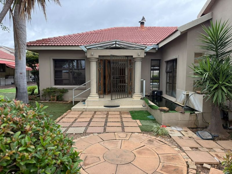 Front entrance of a house featuring a tiled roof, decorative columns, a security gate, and a small built-in water feature.