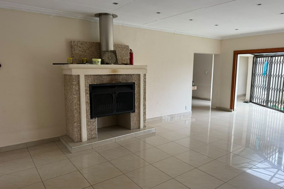 Spacious living area featuring large floor tiles, a prominent built-in fireplace with mosaic detailing, and recessed ceiling lighting.