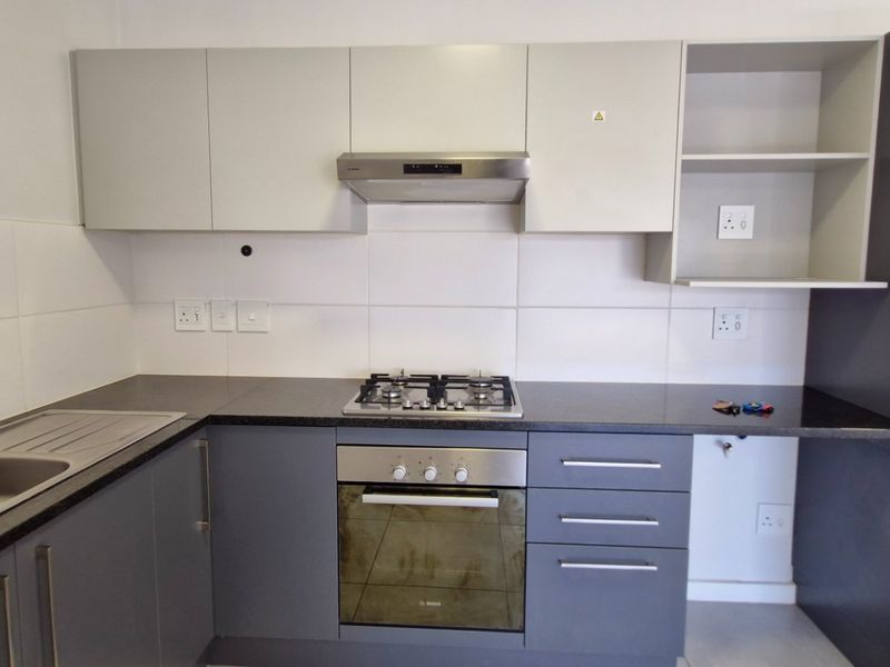 Modern kitchen featuring dark grey and light grey cabinetry, granite countertops, a gas hob, built-in oven, and a double sink with tiled splashback.