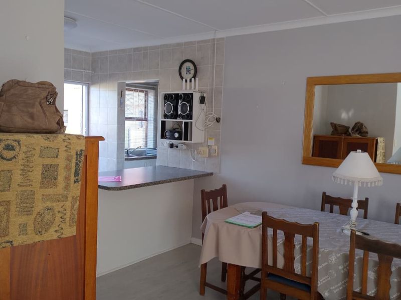 Open plan dining area featuring laminate flooring and a breakfast bar connecting to the kitchen space.