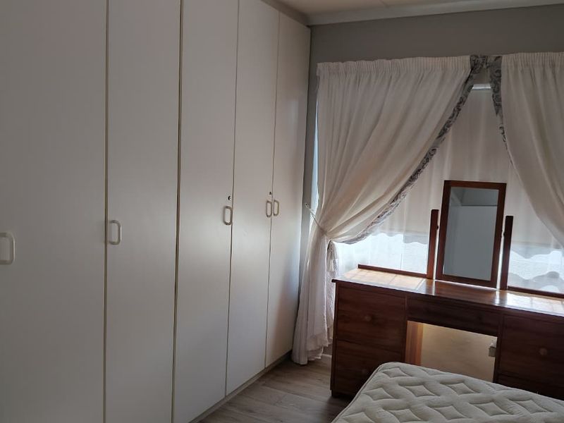 A bedroom featuring extensive floor-to-ceiling built-in cupboards and laminate flooring, providing ample storage space.