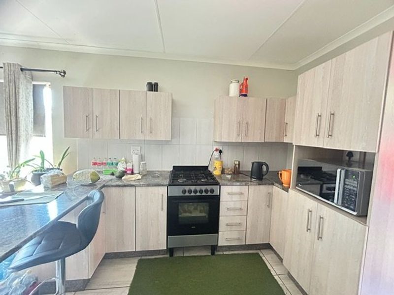 A functional kitchen featuring light wood-look cabinetry, granite countertops, a gas stove with oven, and a built-in microwave.